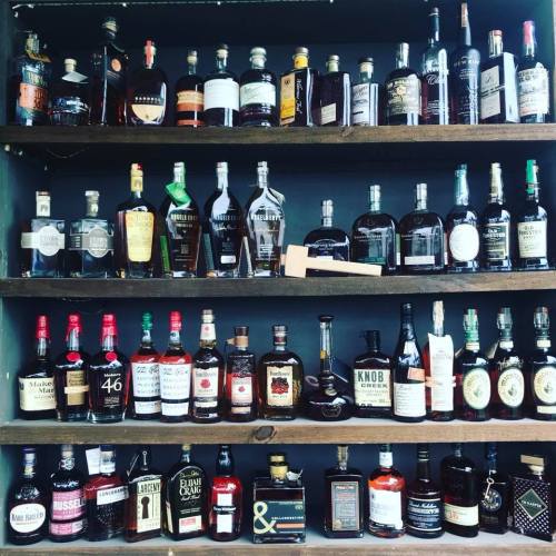 A wooden shelf displaying a variety of whiskey and liquor bottles arranged neatly.
