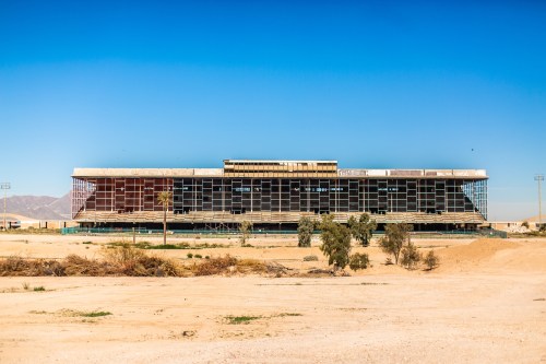 Abandoned building in a desert landscape, featuring a modern design with large windows and a clear blue sky.