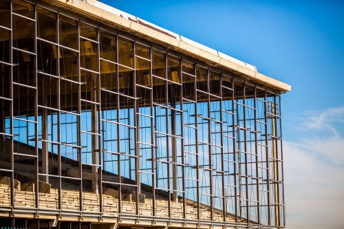 Modern building facade with large glass windows and a concrete structure against a clear blue sky.