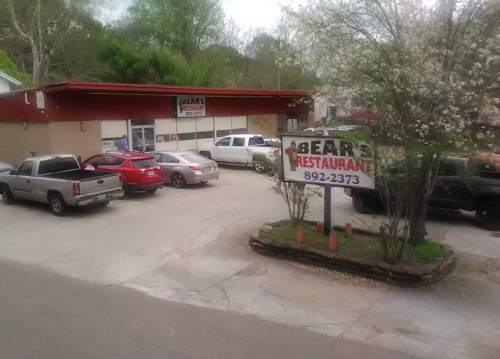 A restaurant named "Bear's" with a parking lot filled with cars and trees in the background.
