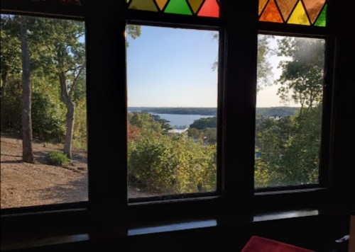 View of a serene lake and trees through a stained glass window, with sunlight illuminating the scene.