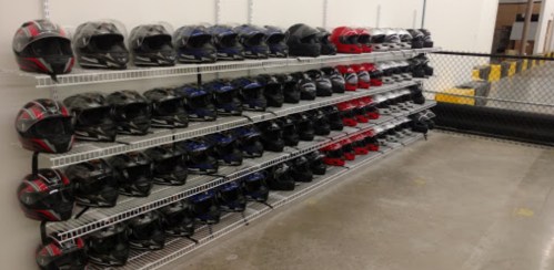 A wall-mounted shelf displaying a variety of helmets in different colors, neatly arranged in rows.
