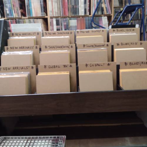 A wooden display with labeled sections for music genres like Jazz, Country, Gospel, and New Arrivals.