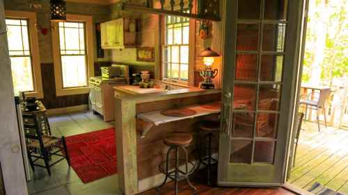 Cozy kitchen with wooden accents, a bar area, and large windows overlooking a deck. Warm, inviting atmosphere.