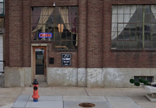 A brick building with large windows, an "OPEN" sign, and a fire hydrant in front.