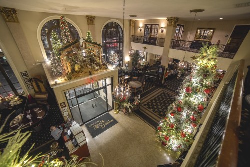 A festive lobby decorated for Christmas, featuring a large tree, nativity scene, and elegant holiday decor.