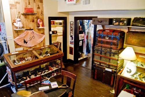 A cozy vintage shop filled with antique trunks, shoes, and unique decor items on display.