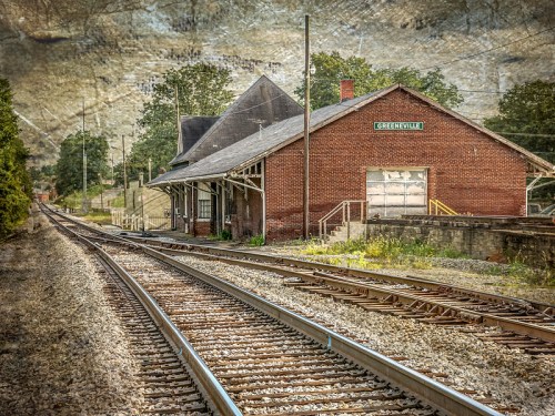 Abandoned train station in Greenville, with tracks leading into the distance and a textured background.