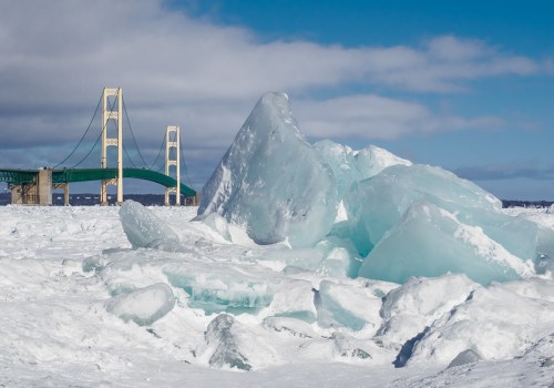 A frozen landscape with large ice formations in the foreground and a bridge in the background under a blue sky.