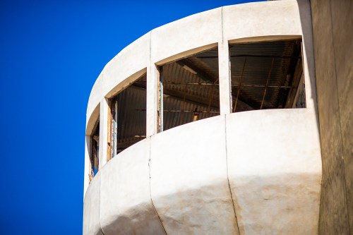 A close-up of a curved building section with large windows against a clear blue sky.