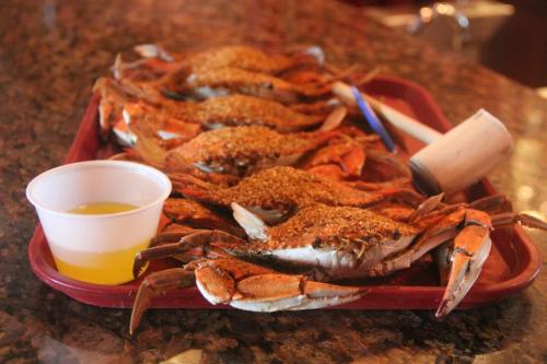 A tray of seasoned crabs with a small cup of sauce, set on a granite countertop.