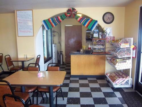 Cozy restaurant interior with checkered floor, wooden tables, and a colorful decoration above the counter.