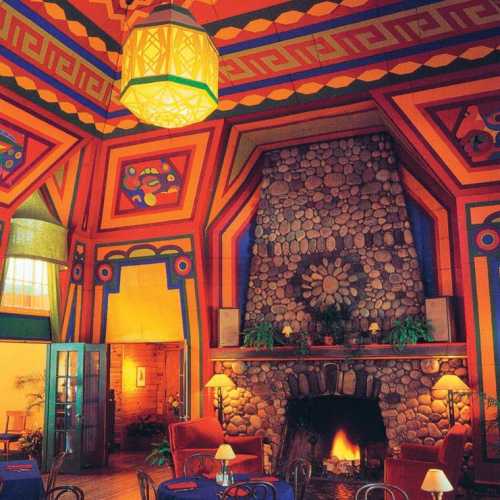 Colorful interior featuring a patterned ceiling, stone fireplace, and cozy seating in a vibrant, artistic space.