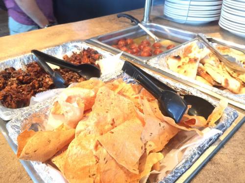A buffet spread featuring various dishes, including crispy snacks, meat, and bread, with serving utensils.