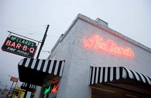 Signage for McClard's Bar-B-Q, featuring neon lights and a striped awning on a foggy day.