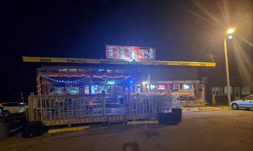 A nighttime view of a BBQ restaurant with colorful lights and a sign reading "BBQ Blues."