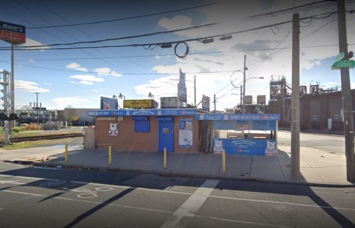A small, blue and beige building with a Pepsi sign, located near a street and power lines, under a clear sky.