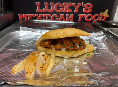 A sandwich with grilled chicken, onions, and sauce on a toasted bun, served with grilled onions on the side.