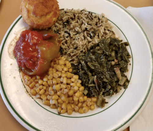 A plate of food featuring rice, collard greens, corn, stuffed peppers, and a cornbread muffin.