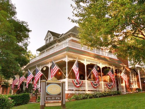 A charming house adorned with American flags and bunting, surrounded by lush greenery.