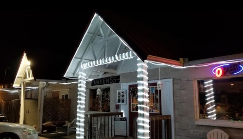 A cozy building at night, adorned with white string lights and an "Open" neon sign.