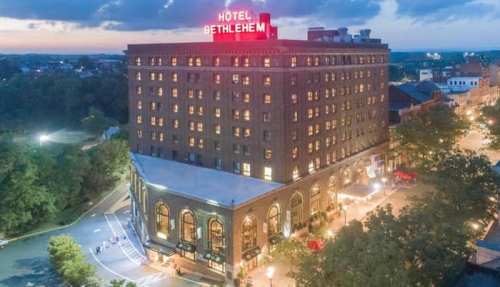 Aerial view of Hotel Bethlehem, a historic building with a red neon sign, surrounded by trees and city streets.
