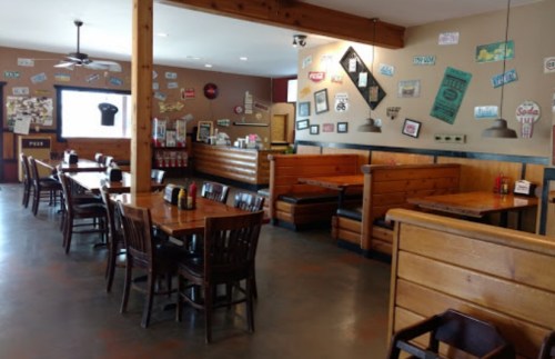 Interior of a casual restaurant featuring wooden tables, chairs, and walls decorated with various signs and memorabilia.