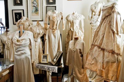 A collection of vintage wedding dresses displayed on mannequins in a cozy, well-lit room.