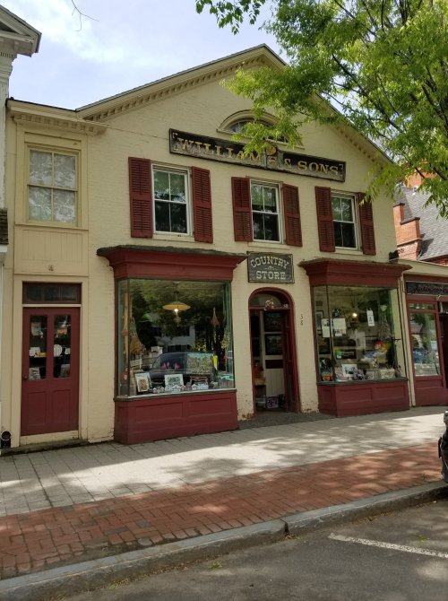 A charming country store with red shutters and a sign reading "William & Sons" on a sunny day.