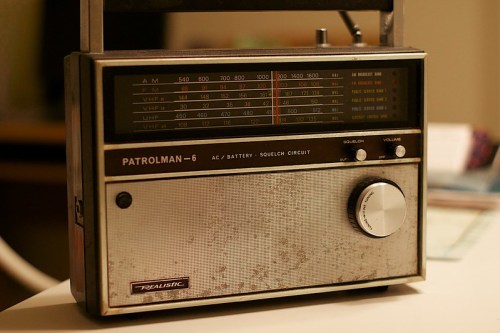 A vintage Realistic Patrolman-6 radio with a worn exterior, featuring AM and VHF frequency dials and a volume knob.