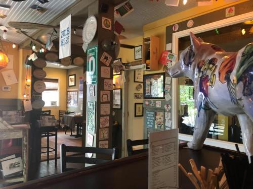 A colorful horse statue stands in a cozy restaurant filled with eclectic decor and framed signs on the walls.