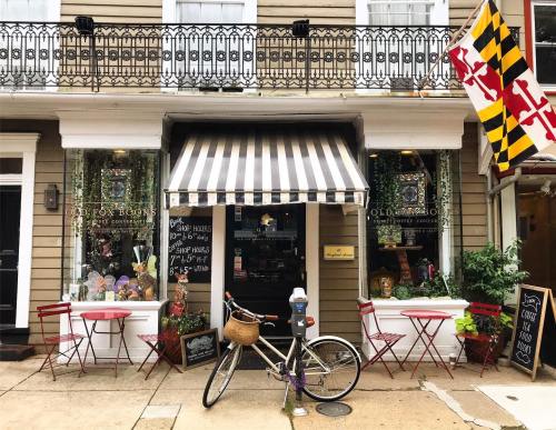 A quaint bookstore with a striped awning, outdoor seating, and a bicycle parked outside, featuring a Maryland flag.