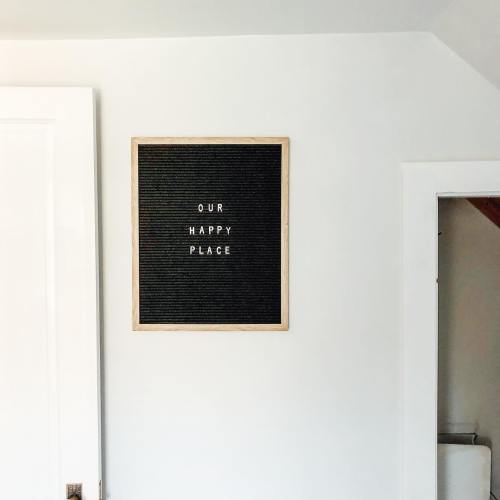 A wall with a framed letter board displaying the text "OUR HAPPY PLACE" in a cozy, light-colored room.