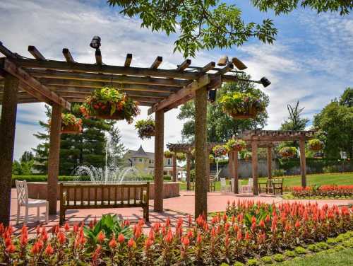 A vibrant garden with wooden pergolas, hanging plants, a fountain, and colorful flower beds under a blue sky.