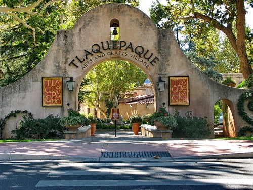 Entrance to Tlaquepaque Arts and Crafts Village, featuring a decorative archway and lush greenery.