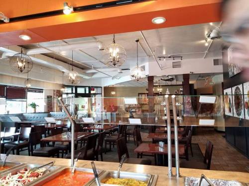 Interior of a restaurant featuring a buffet area, tables, and modern lighting fixtures.