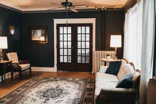 Cozy living room with dark walls, a patterned rug, a vintage sofa, and French doors leading to an outdoor space.