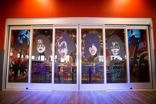 Colorful glass doors featuring stylized portraits of rock band members with vibrant backgrounds and signatures.
