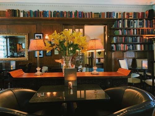 Cozy library-style cafe with bookshelves, a floral centerpiece, and warm lighting creating an inviting atmosphere.