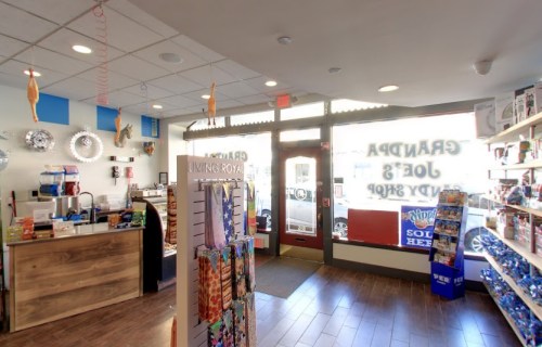 Interior of a colorful gift shop with shelves of items, a checkout counter, and large windows letting in natural light.