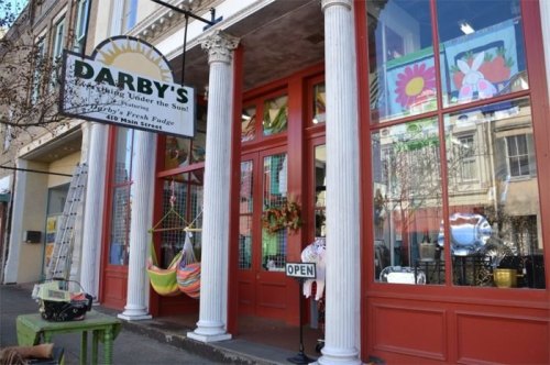 Storefront of Darby's, featuring colorful window displays, a sign that says "OPEN," and decorative columns.