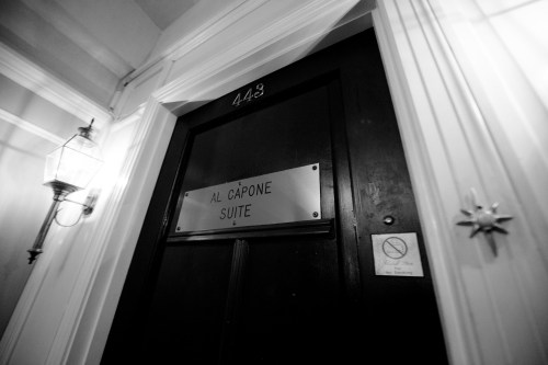 A close-up of a door labeled "Al Capone Suite," with a lantern and decorative wall features nearby.
