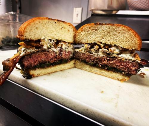 A juicy burger with a thick patty, topped with creamy sauce and crispy onions, served in a toasted bun.