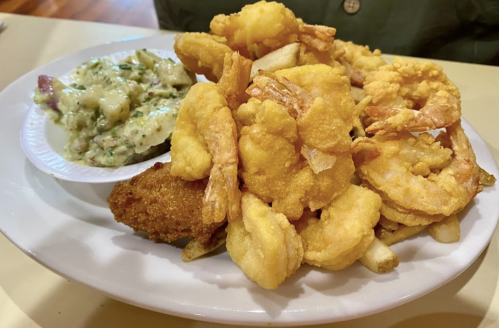 A plate of golden fried shrimp, hushpuppies, and a side of creamy coleslaw.