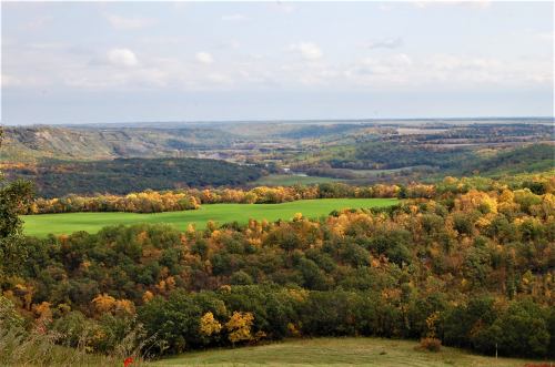 A scenic view of rolling hills and valleys, featuring vibrant autumn foliage and a clear sky.