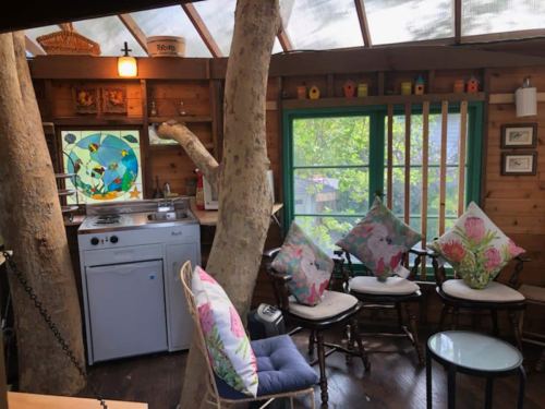 Cozy interior of a wooden cabin with a washing machine, colorful pillows, and large windows overlooking greenery.
