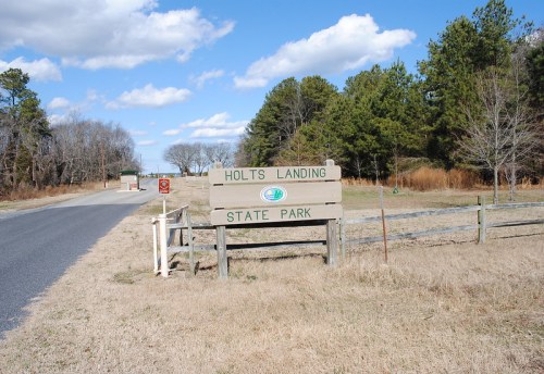 Sign for Holts Landing State Park at the entrance, with a clear blue sky and trees in the background.