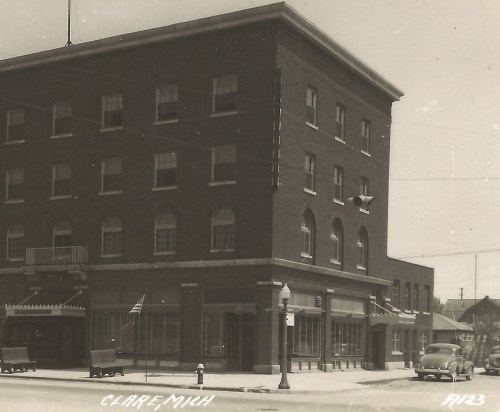 Historic brick building in Clare, Michigan, featuring large windows and a flag, captured in black and white.