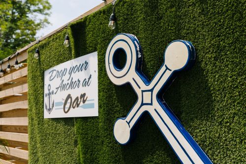 A blue anchor decoration on a green wall with a sign that reads "Drop your Anchor at Oar."