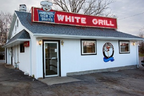 A small, white building with a red sign reading "White Grill," featuring a cartoon chef and a door entrance.